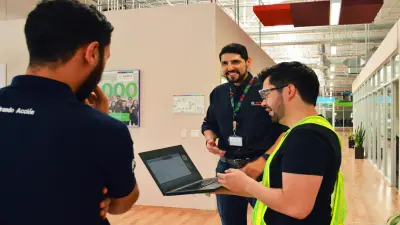 Dos empleados de Bosch, una mujer y un hombre, están sentados en un sofá, teniendo una conversación amigable. La mujer está sosteniendo un portátil. Ambos están usando camisetas con el logotipo “#LikeABosch”.